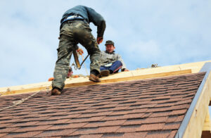 Two roofing technicians installing a new shingle roof